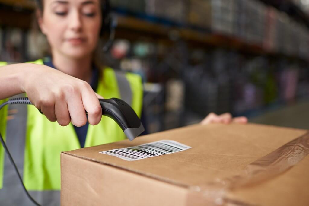 Woman using barcode reader on a box in a warehouse, detail